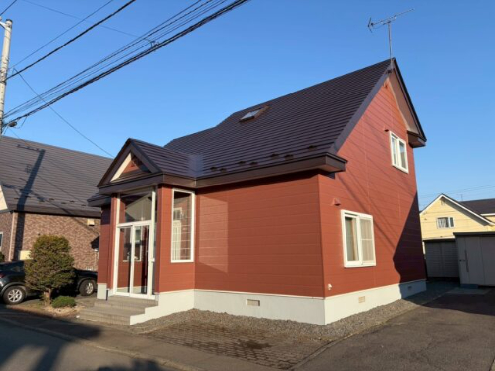 落ち着いた赤茶色のガルバリウム鋼板外壁とダークブラウンの屋根、白いサッシを組み合わせた苫小牧市T様邸の外観写真。